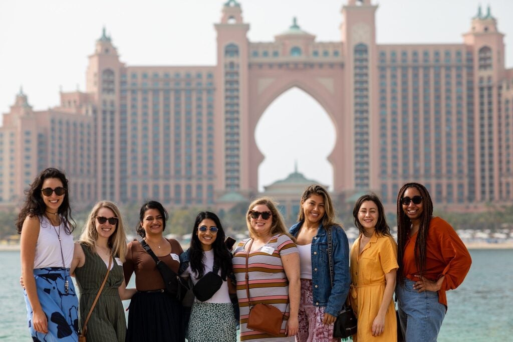 Students in the UAE standing in front of a unique building with a arch in the middle of it